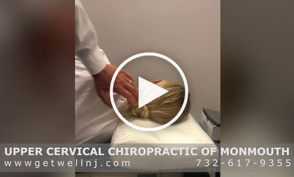 Doctor from Upper Cervical Chiropractic of Monmouth NJ touching head of patient lying down