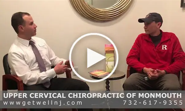 Nicely dressed man sitting and talking to another man in chairs at Upper Cervical Chiropractic of Monmouth