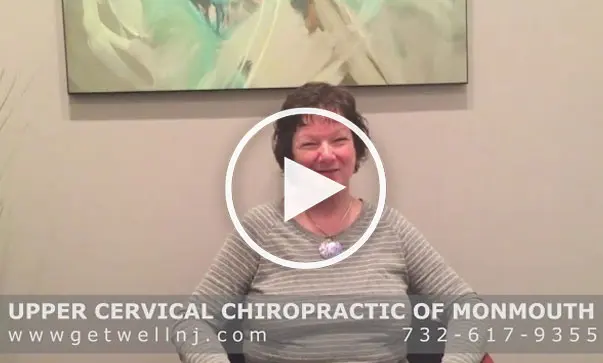 Woman smiling and sitting in chair of room at Upper Cervical Chiropractic of Monmouth