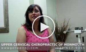Woman in pink shirt sitting in patient room at Upper Cervical Chiropractic of Monmouth NJ
