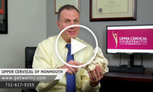 Doctor holding a body part object and talking in office at Upper Cervical Chiropractic of Monmouth NJ