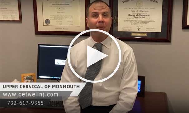 Doctor leaning against desk in office at Upper Cervical Chiropractic of Monmouth and talking