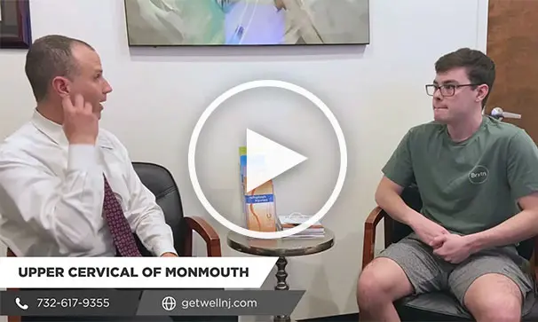 Nicely dressed man talking to a young man as they sit in chairs at Upper Cervical Chiropractic of Monmouth