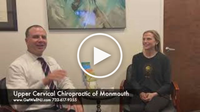 Nicely dressed man talking and sitting next to a woman in chairs at Upper Cervical Chiropractic of Monmouth