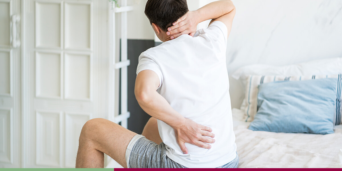 Man stretching on bed with aching back and neck